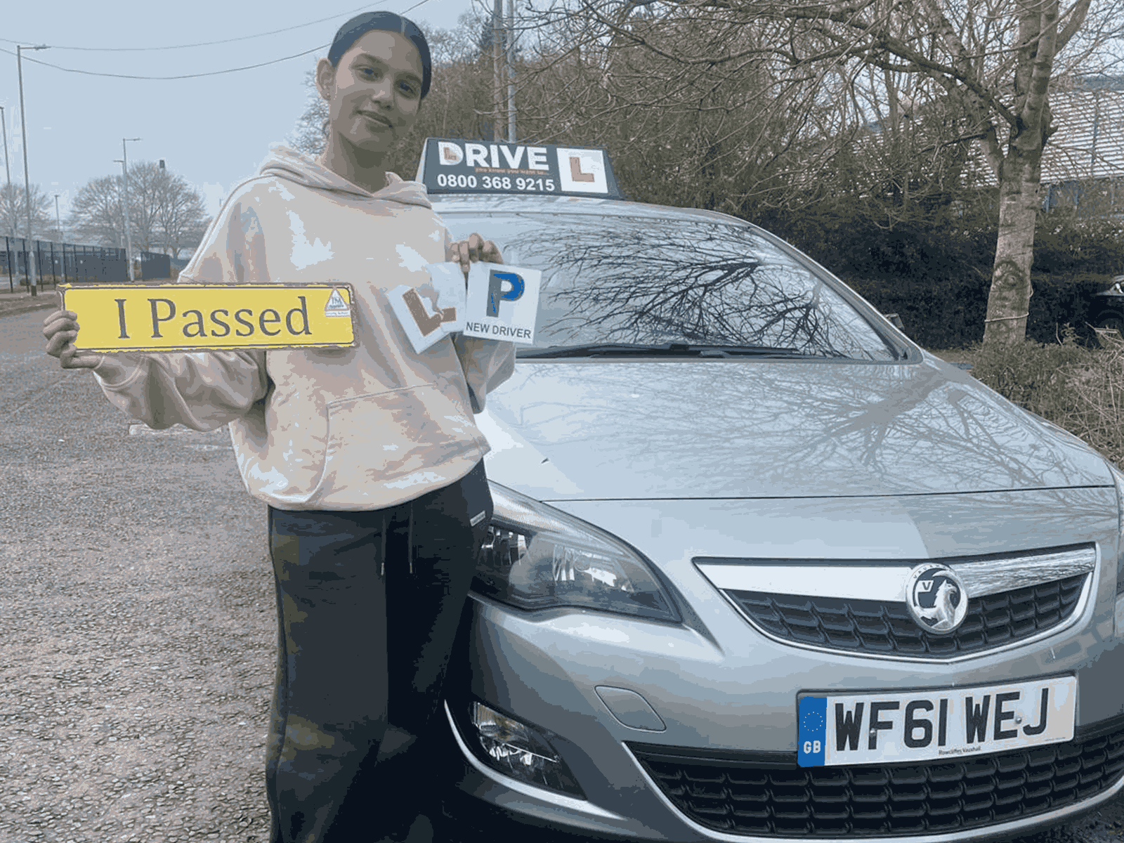 Frazia holding an I Passed sign beside a JM Drive car